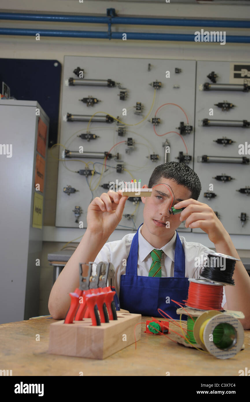 Un ragazzo durante una lezione di GCSE apprendimento pratico circa l'elettronica e la tecnologia di progettazione Foto Stock