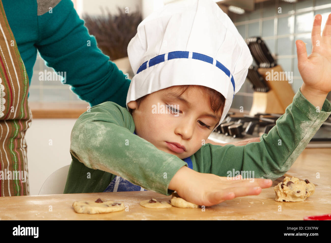 Ragazzo giovane rendendo i cookie in cucina Foto Stock