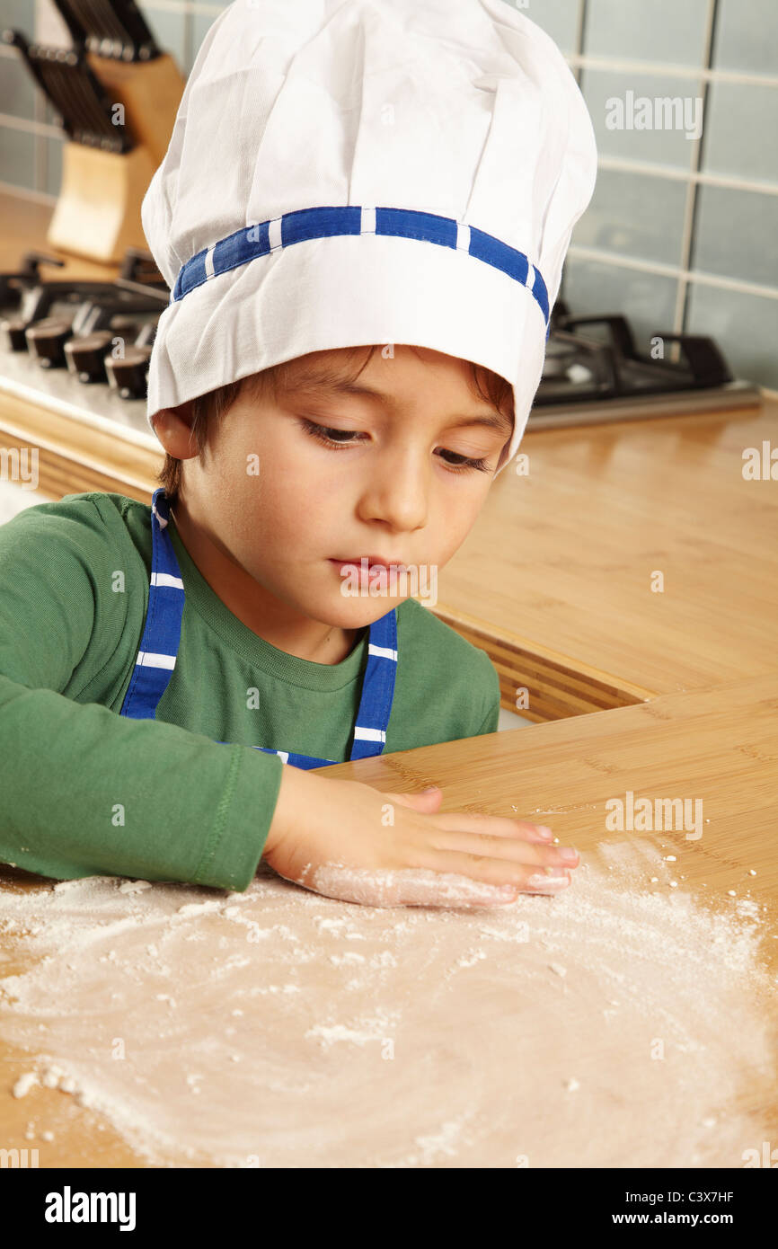 Giovane ragazzo giocando con la farina sul piano portapaziente Foto Stock