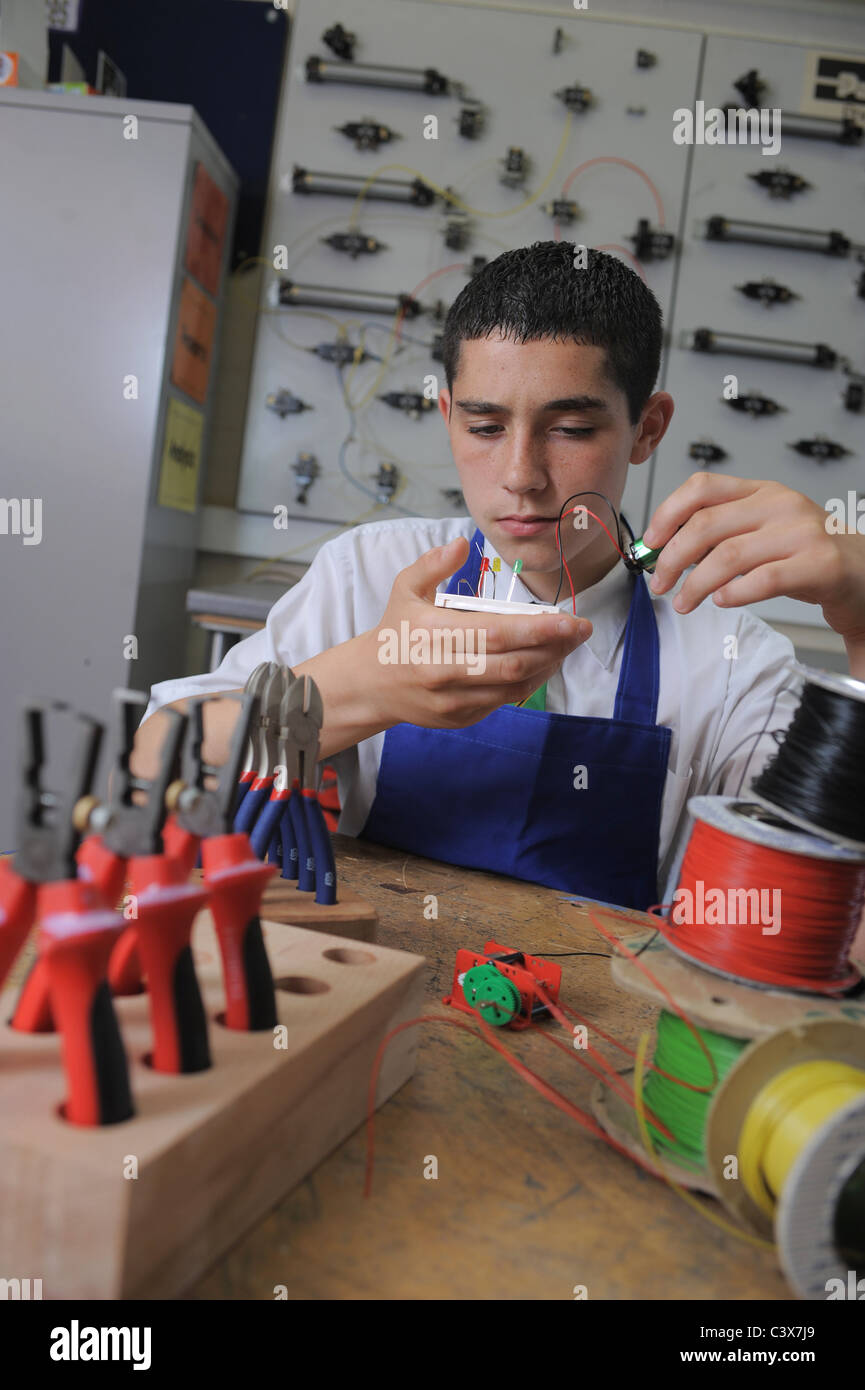 Un ragazzo durante una lezione di GCSE apprendimento pratico circa l'elettronica e la tecnologia di progettazione Foto Stock