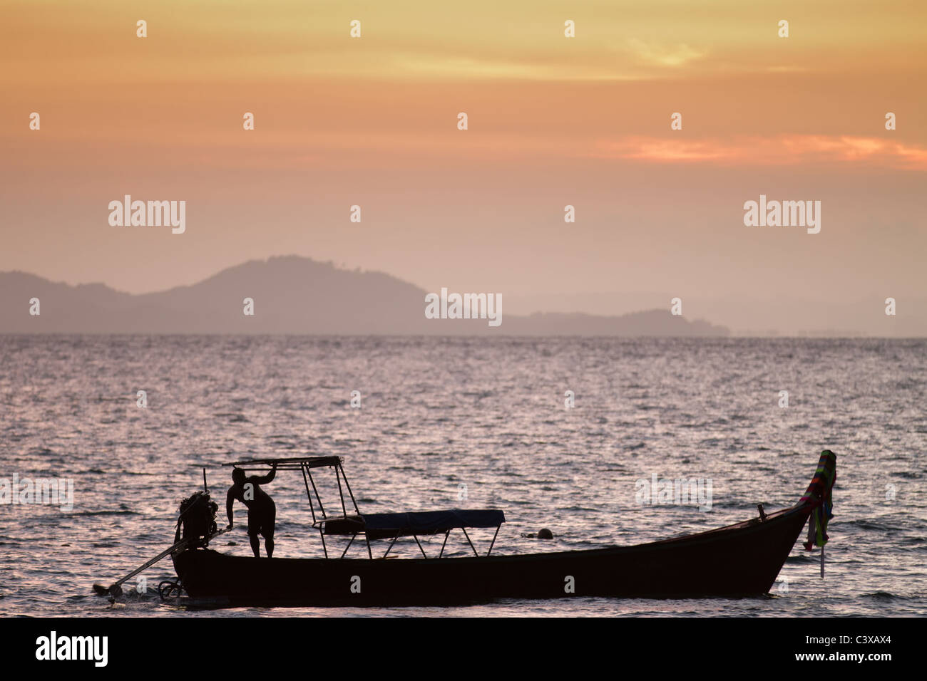 Pescatore e silhouette in barca al tramonto, Thailandia Foto Stock