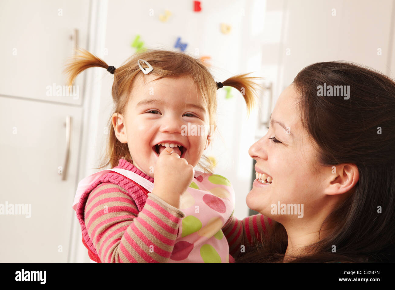 Madre e figlia ridere in cucina Foto Stock