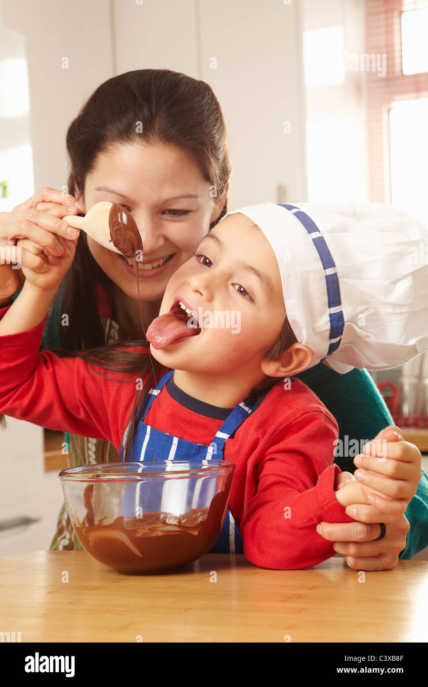 Ragazzo leccare il cioccolato off cucchiaio con la mamma Foto Stock