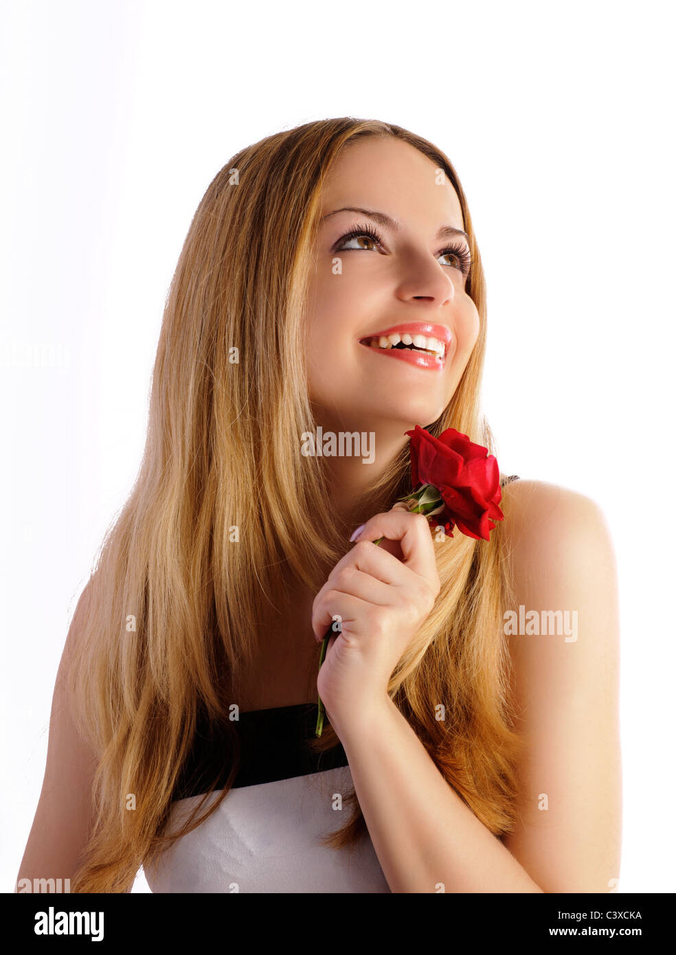 Bella ragazza tenendo un fiore, sorridente e guardando qualcosa al di sopra di lei, isolato Foto Stock