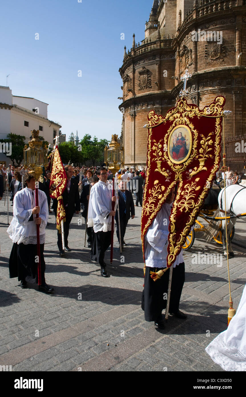 Una processione religiosa a partire dalla cattedrale di Siviglia, Spagna. I sacerdoti portano le lampade con candele e striscioni. Foto Stock