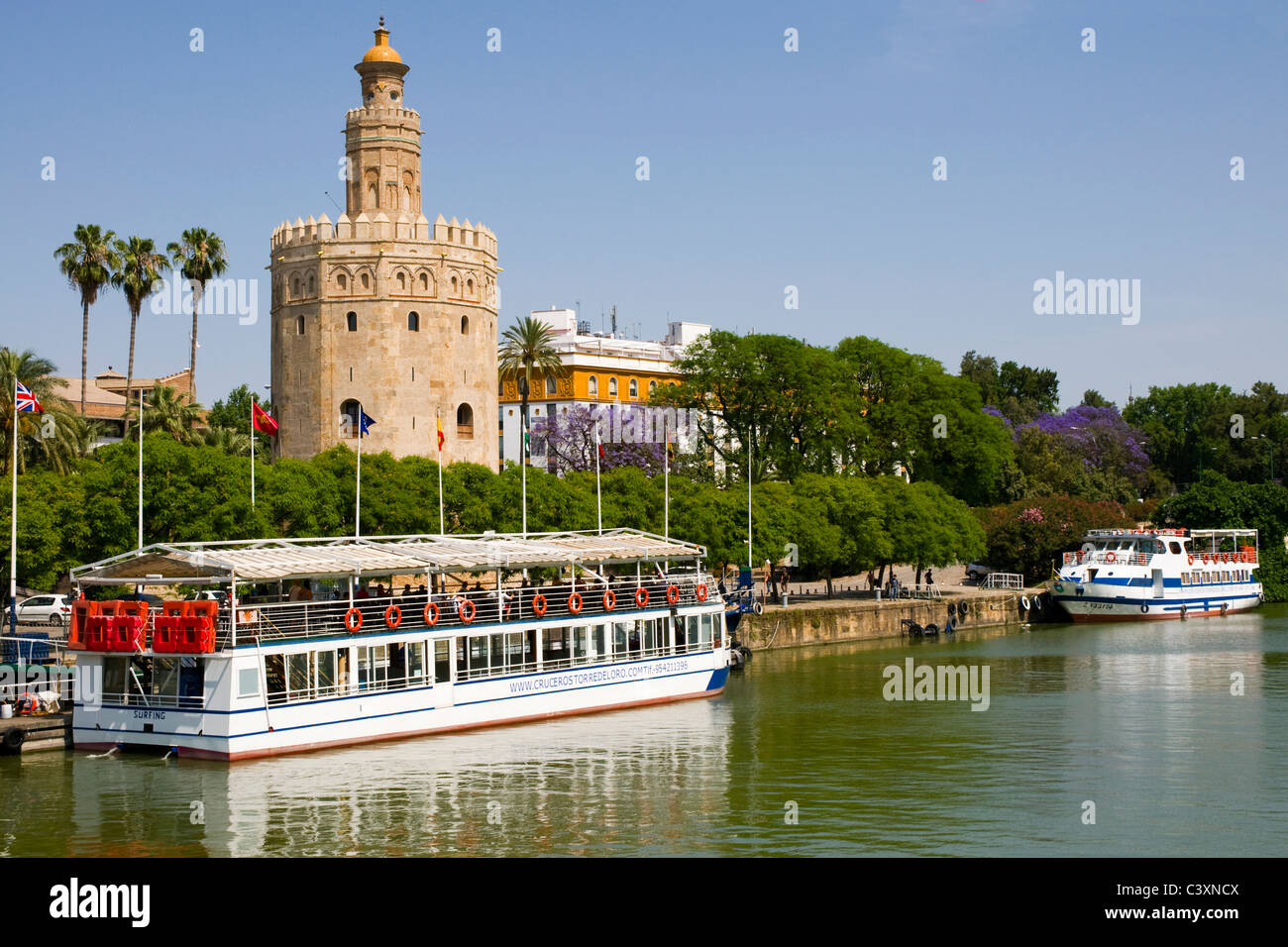 Un turista cruiser ormeggiati davanti alla Torre del Oro o Gold Tower, a Siviglia, in Andalusia, Spagna. Foto Stock