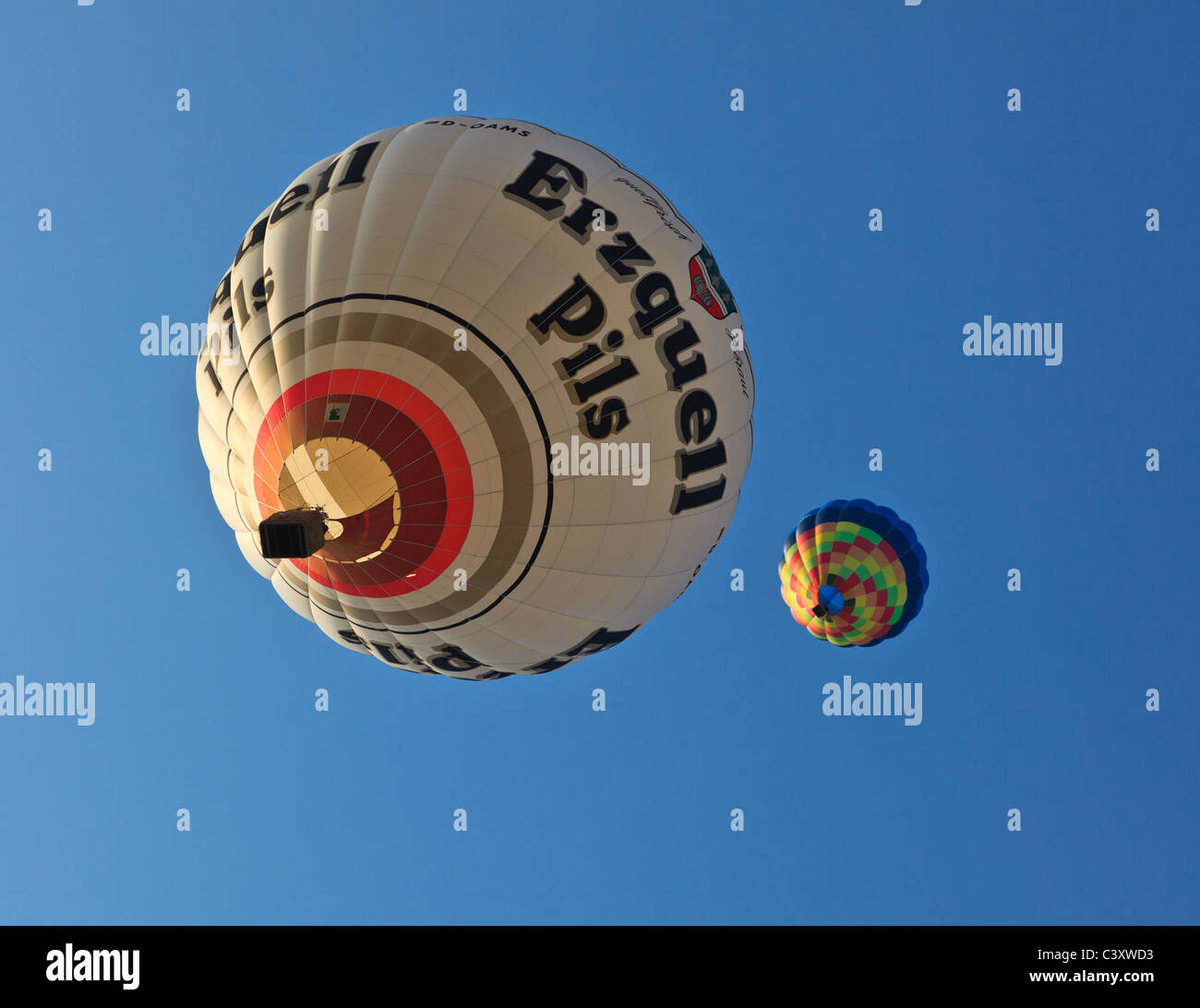Due i palloni ad aria calda su uno sfondo di cielo blu durante il Ferrara Balloons Festival. Un palloncino sponsorizzato da Erzquell pillole, Emilia Romagna, Italia Foto Stock