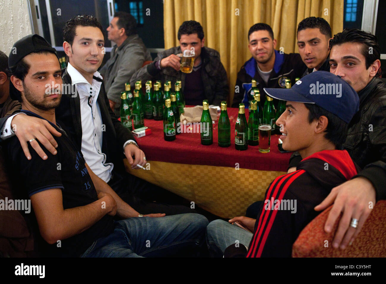 I giovani bere alcolici e fumare sigarette un venerdì sera nel bar dell Hotel Le Colisee a Sfax, Tunisia. Foto Stock