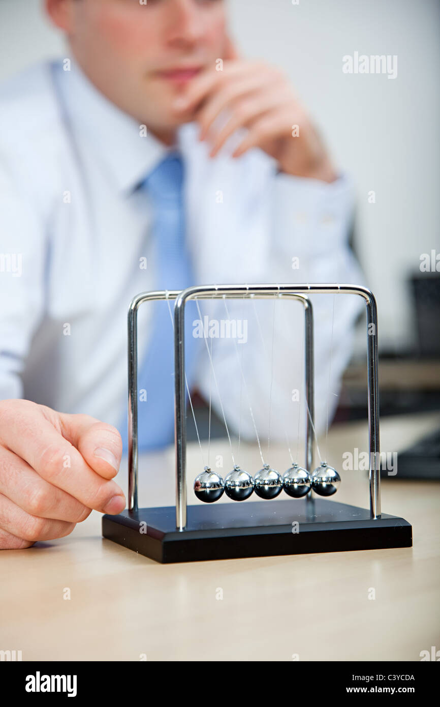 Lavoratore di ufficio giocando con il Newton culla Foto Stock