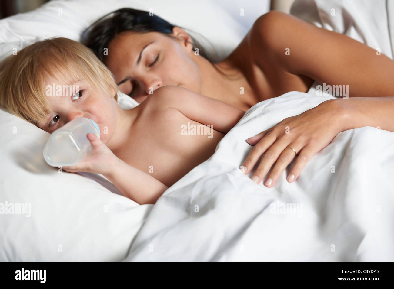 Baby boy borraccia nel letto con MOM Foto Stock