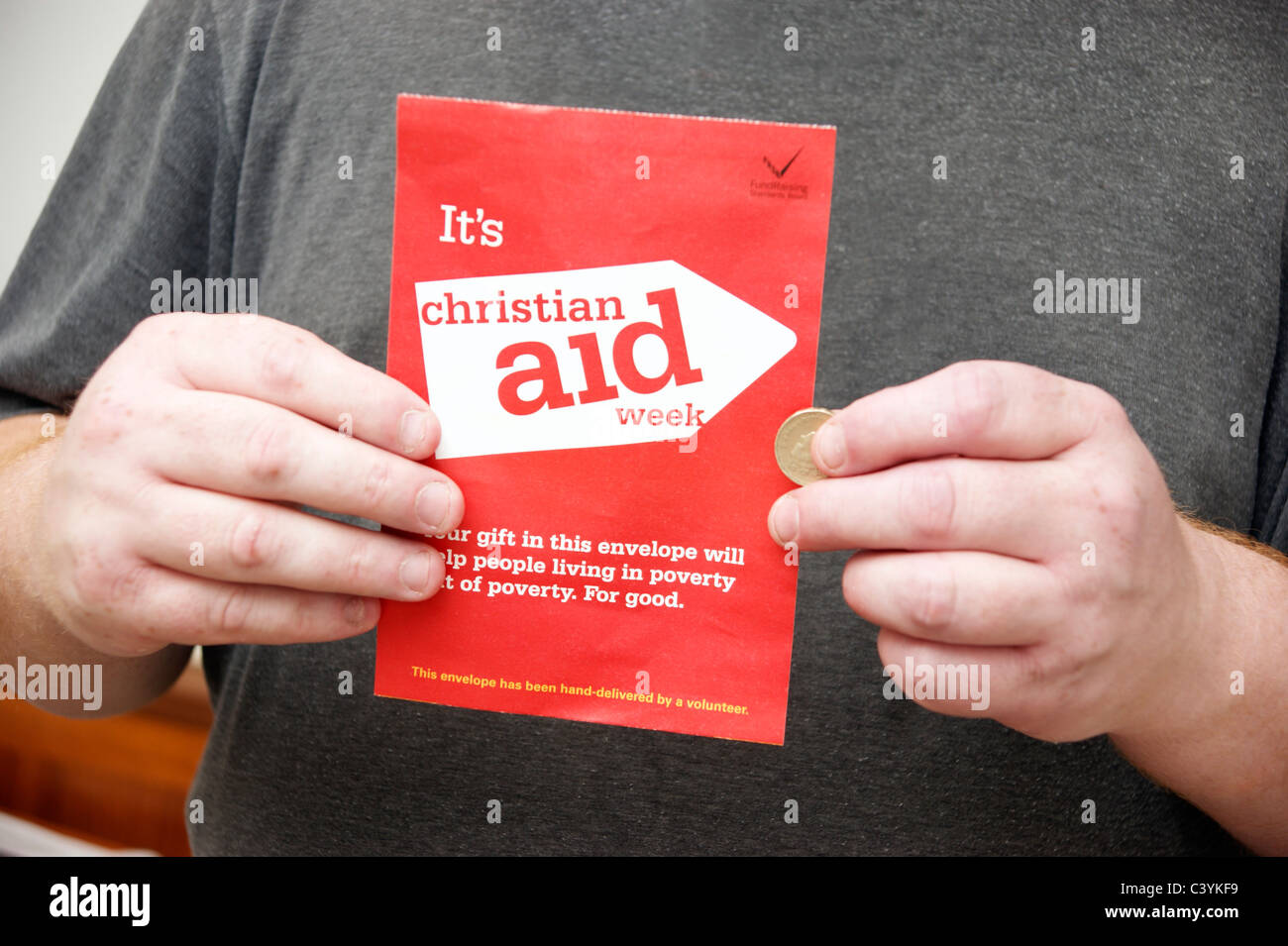 Uomo con la donazione di una moneta per una raccolta di beneficenza busta per Christian Aid settimana Foto Stock