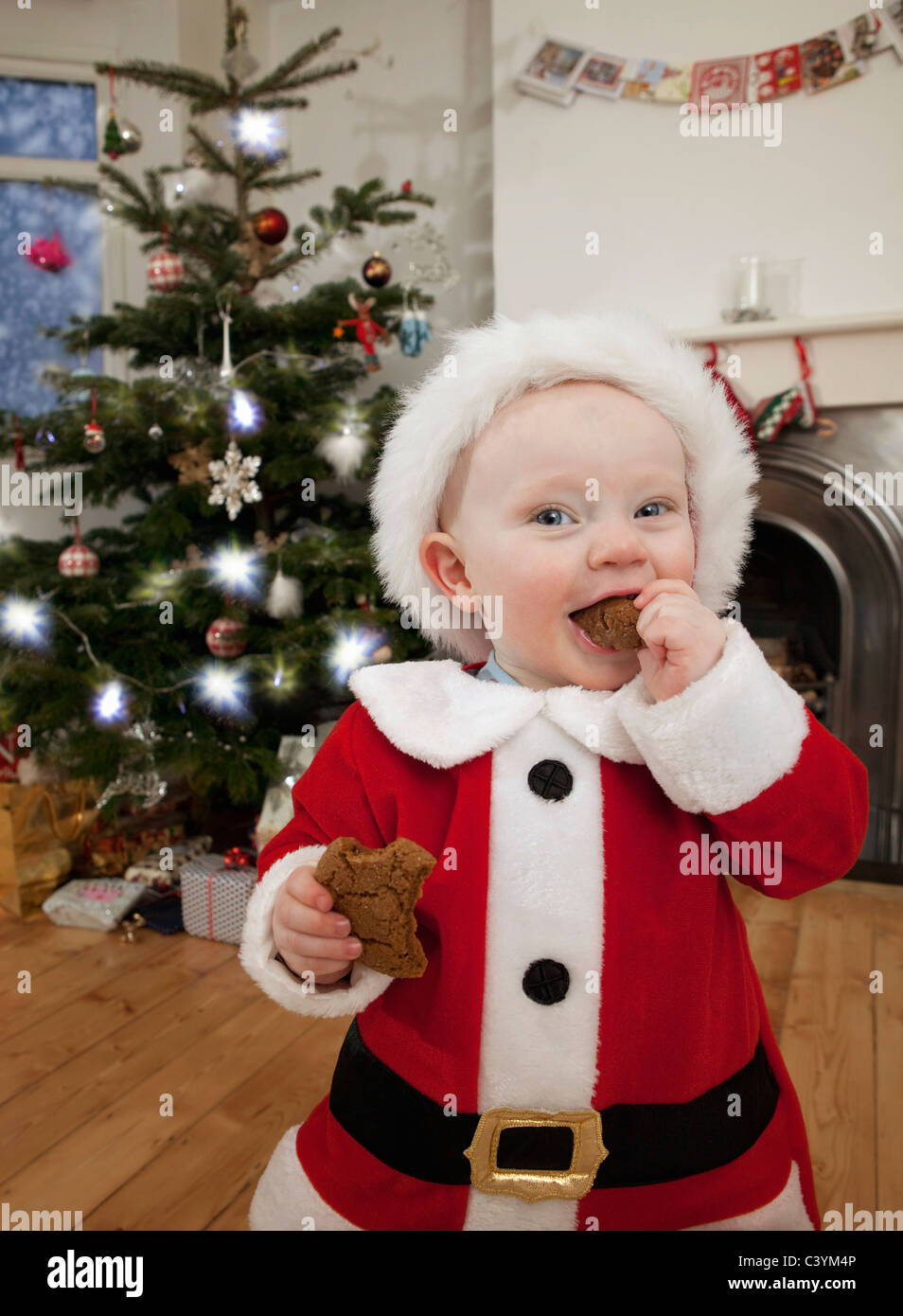 Un bambino vestito come Santa mangiando un biscotto Foto Stock