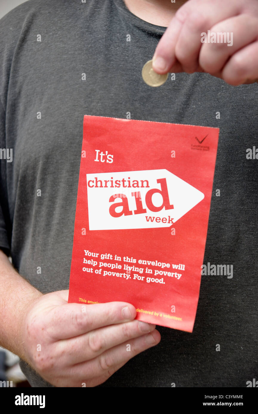 Uomo con la donazione di una moneta per una raccolta di beneficenza busta per Christian Aid settimana Foto Stock