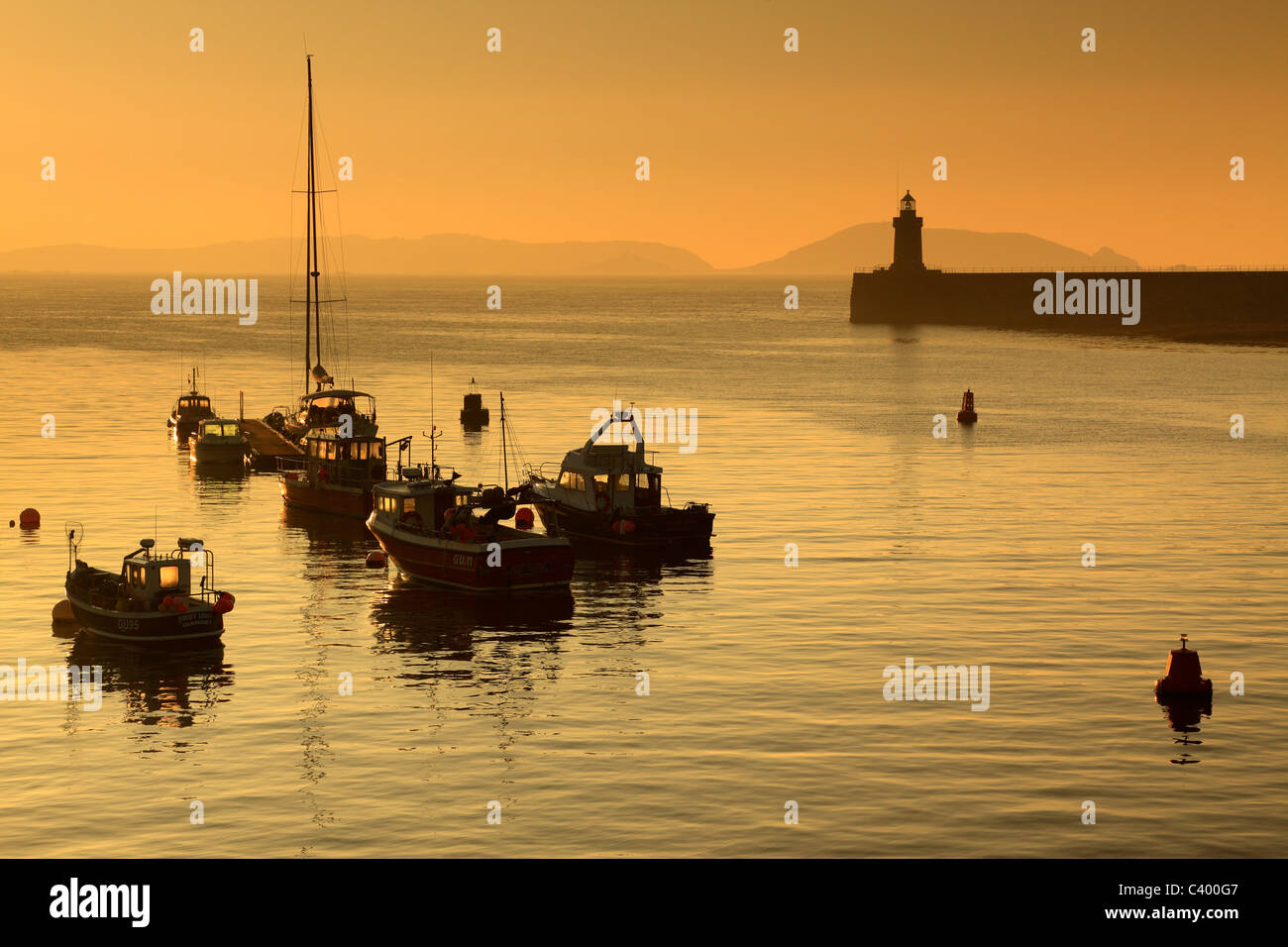 Sole primaverile sul porto di St Peters Porto di Guernsey e di Herm Island visibile in distanza Foto Stock