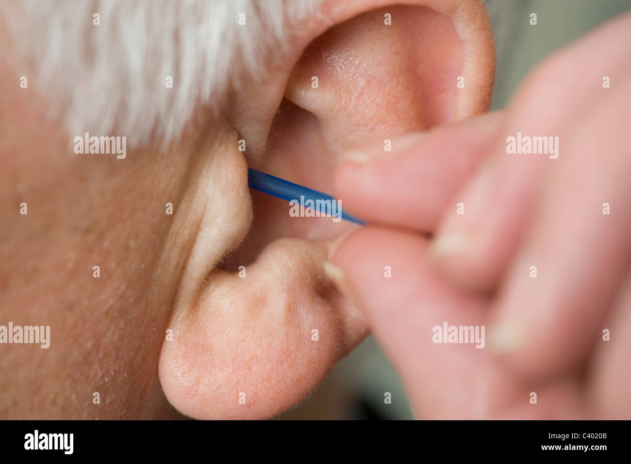 Un uomo che pulisce il suo orecchio con un batuffolo di cotone. Foto Stock