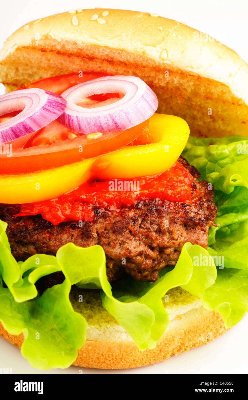 Primo piano di un hamburger con pane, carne, lattuga, salsa, peperoni, pomodori e cipolla Foto Stock