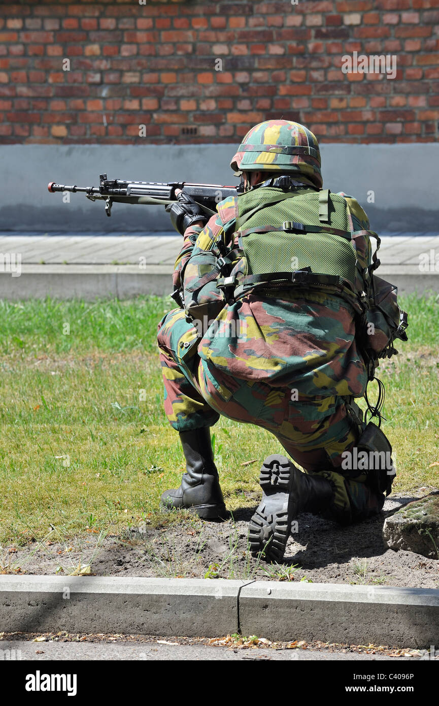 Soldato inginocchiato con FN FNC fucile da assalto riprese in strada durante l'esercizio dell'esercito belga a Leopoldsburg, Belgio Foto Stock