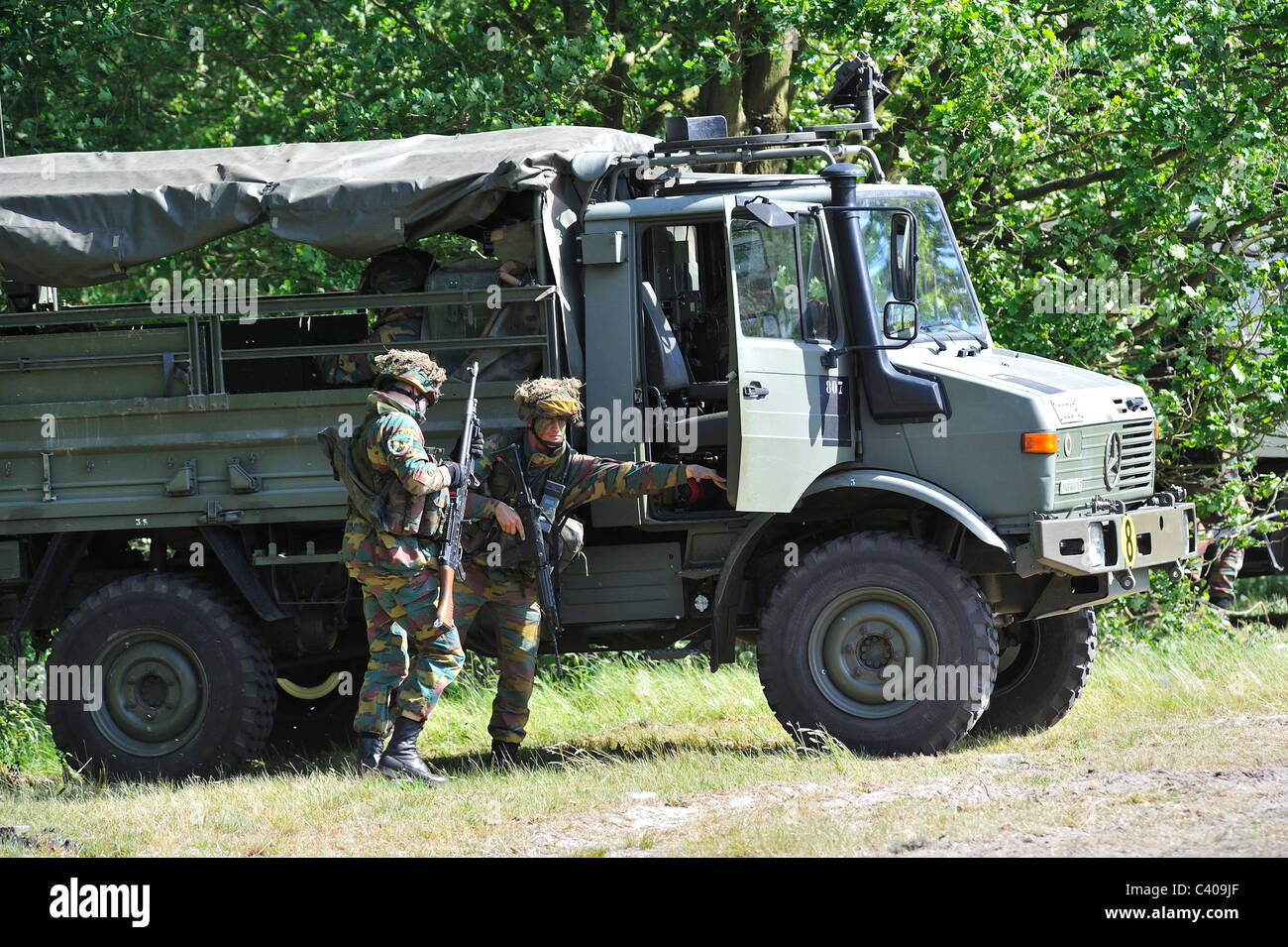 Dimostrazione di soldati di fanteria combattendo nei pressi di U1350L Unimog combattimento blindati veicolo dell'esercito belga, Belgio Foto Stock