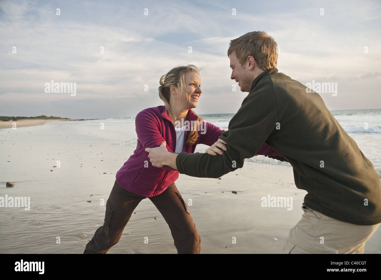 Giovane uomo e donna wrestling a beach Foto Stock