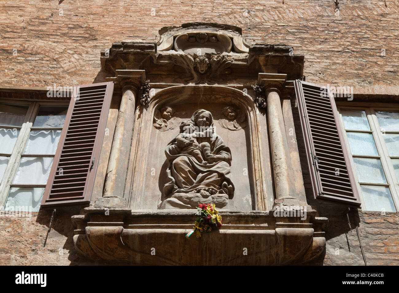 Santa Maria tenendo in braccio Gesù Bambino statua su una casa senese parete. Siena, Toscana, Italia Foto Stock