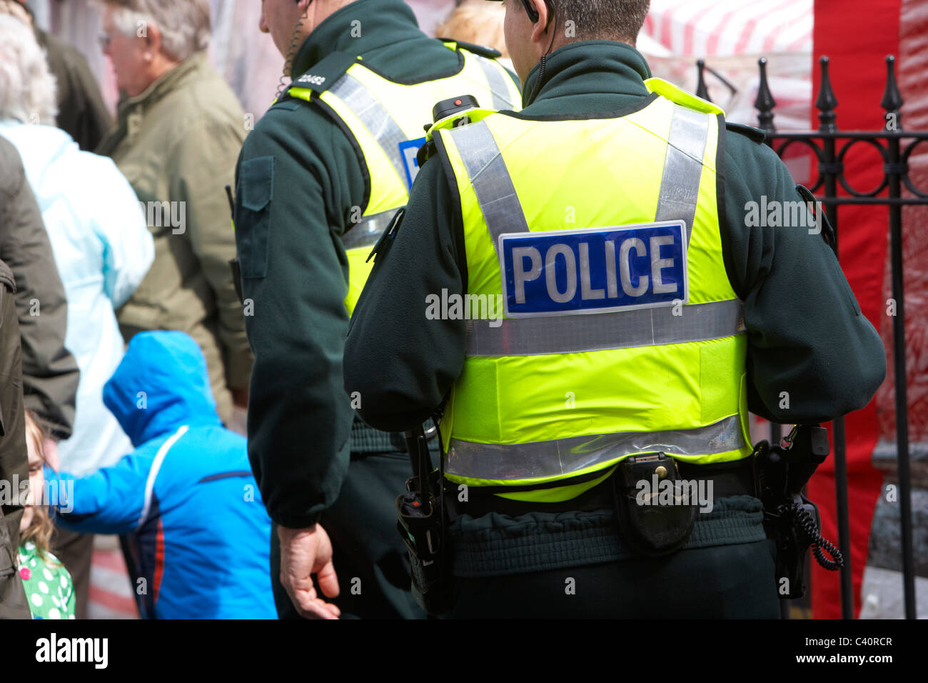 Poliziotti armati indossando stab prova giubbotti antiproiettile a piedi attraverso la folla Foto Stock