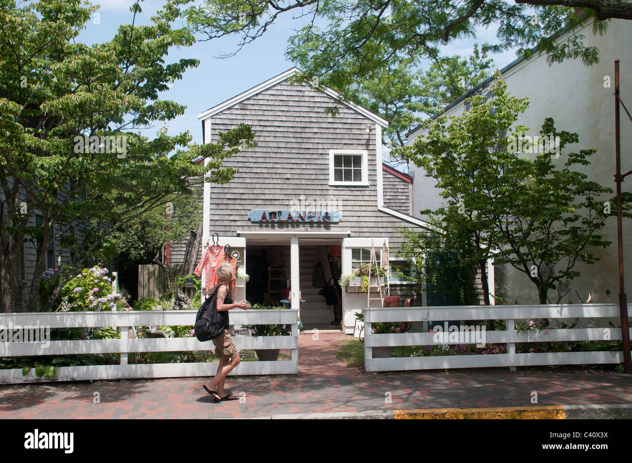 Una donna cammina passato negozi nella città di Nantucket. Foto Stock