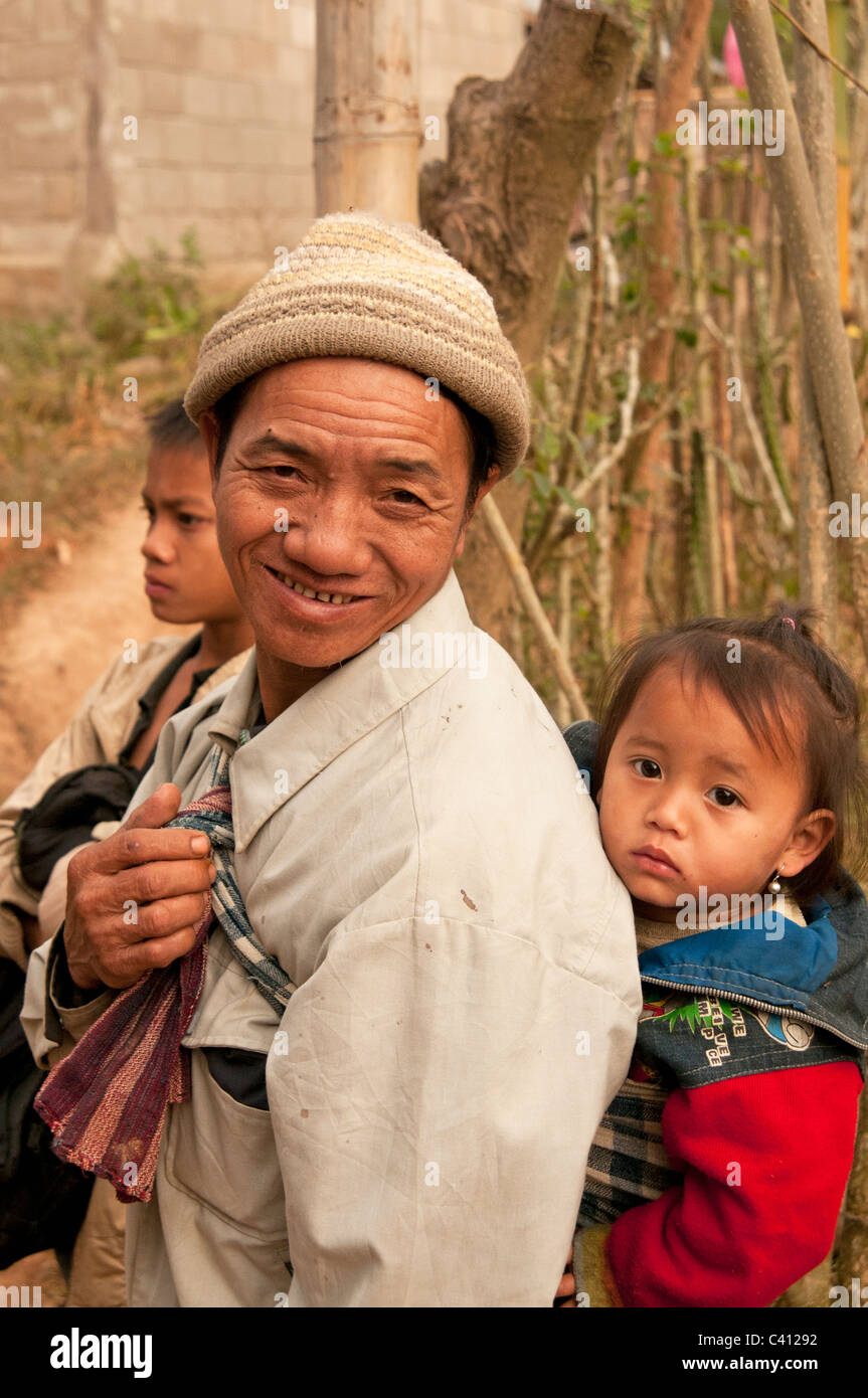Padre Lao e giovani sul baby sling torna al remoto villaggio mercato nel Nord Est Laos Foto Stock