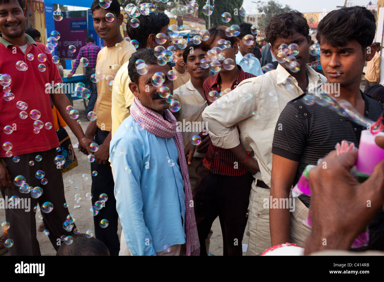 Un uomo soffia bolle di sapone usando una plastica giallo ventilatore al Sonepur Mela a Sonepur in stato di Bihar, in India. Foto Stock