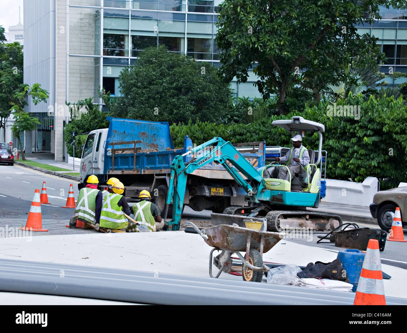 Una gang di strada impresa lavori stradali in una strada di Singapore con un meccanico della macchina di scavo e ribaltabile Asia Foto Stock