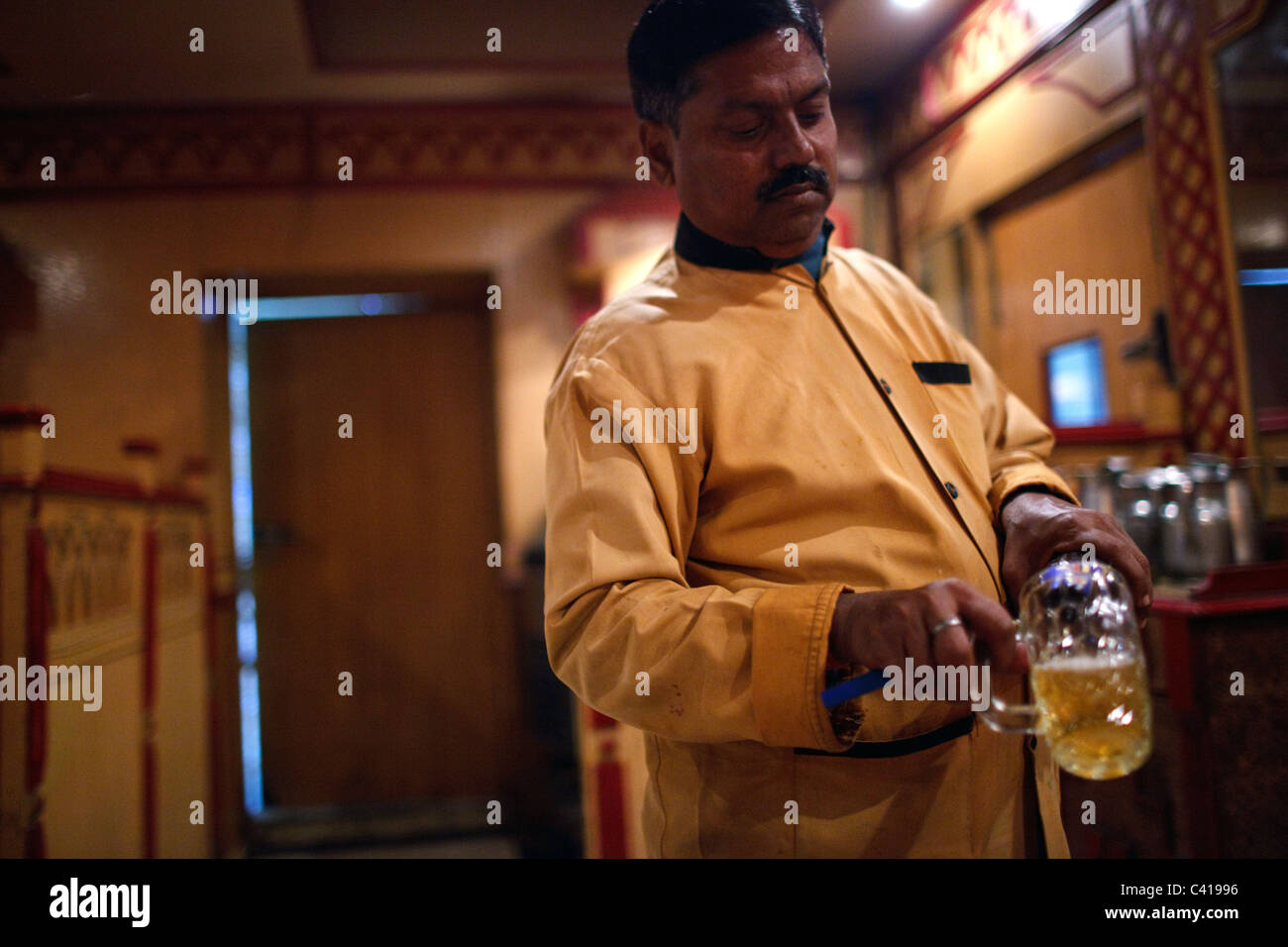 Un cameriere si versa la birra in un bicchiere in un ristorante che serve bevande alcoliche a Patna, Bihar, in India. Foto Stock