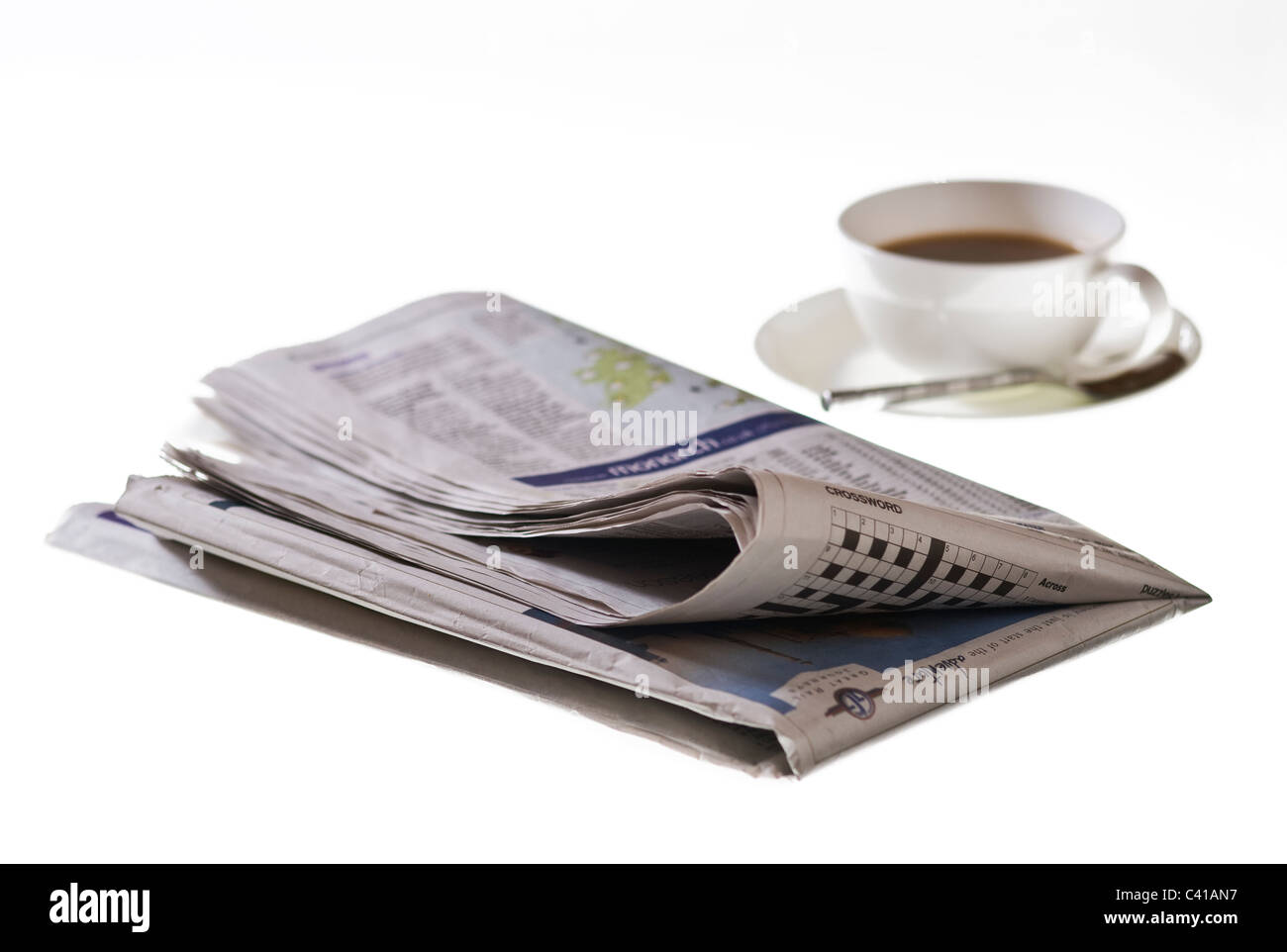 Giornale ripiegato su sfondo bianco, con una tazza di caffè. Foto Stock