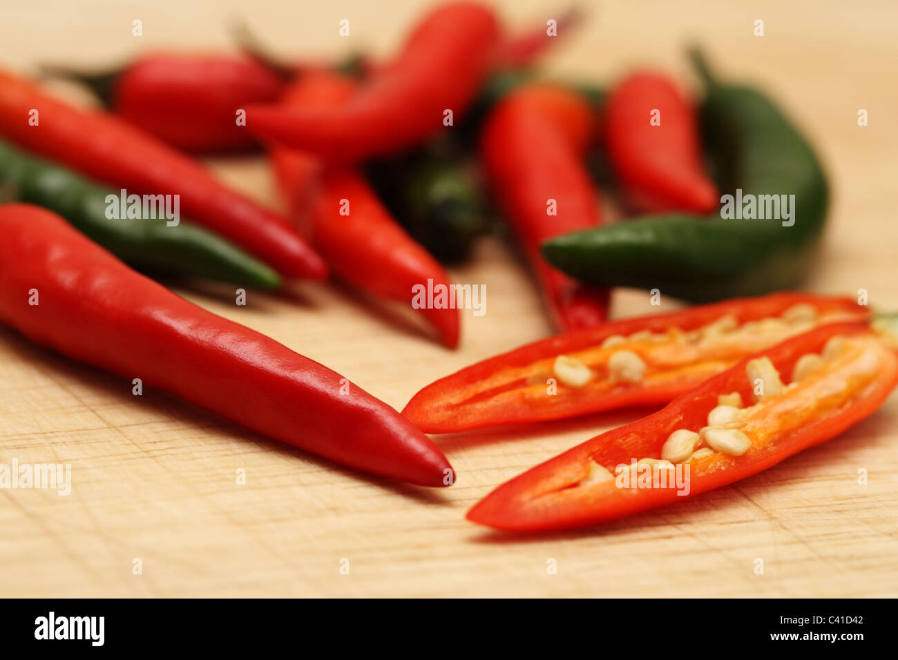 Rosso e peperoncini verdi su un tagliere di legno Foto Stock