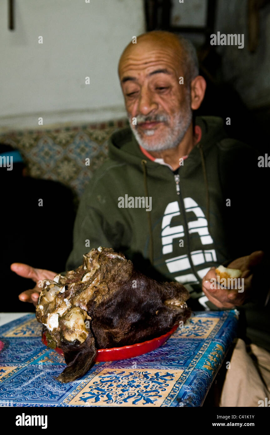 Un marocchino uomo mangiare la testa di pecora per la prima colazione. Foto Stock