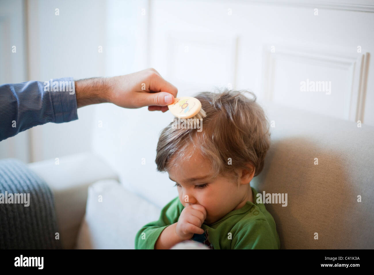 Padre toddler spazzolatura figlio di capelli, ritagliato Foto Stock