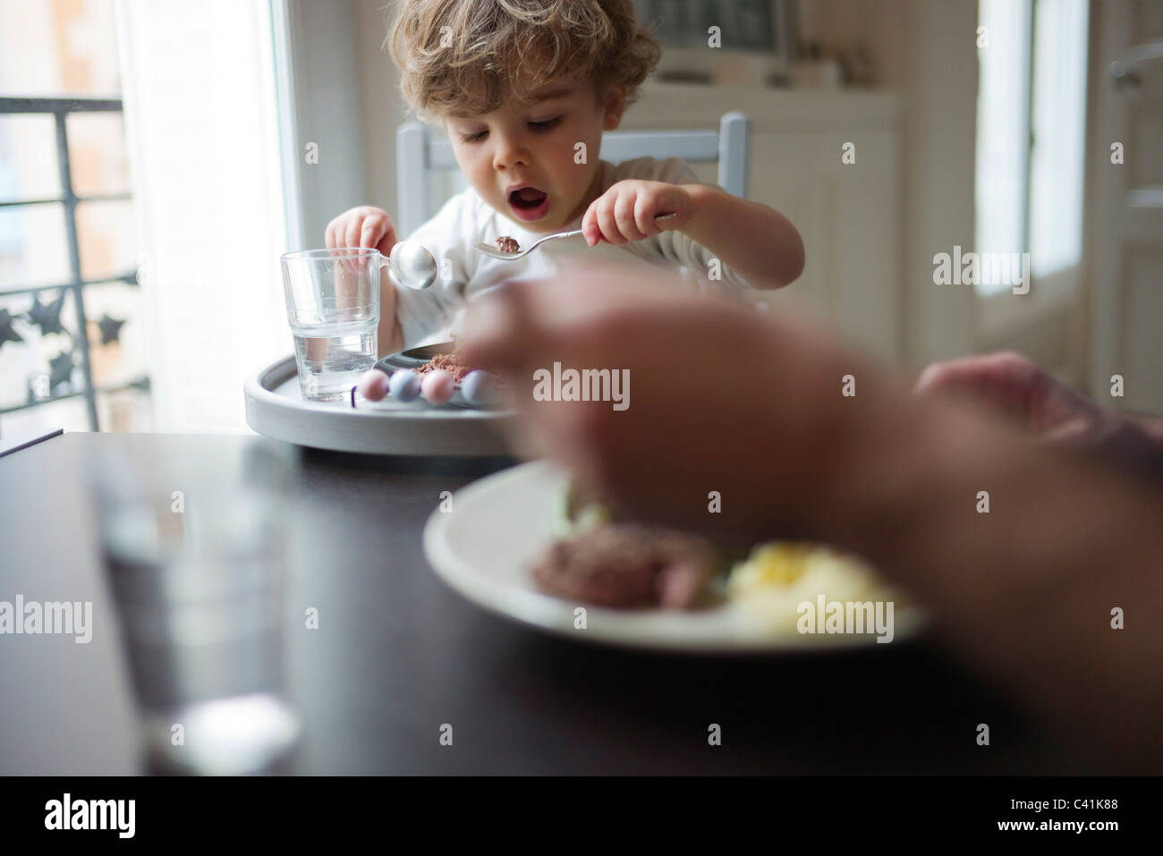 Il Toddler boy mangiare pasti con un genitore Foto Stock