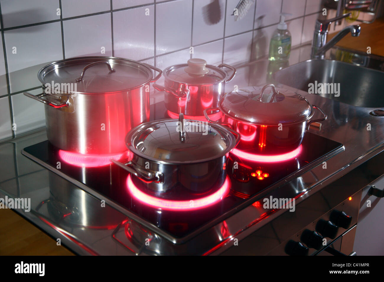 Cucina casalinga, pentole, realizzata in acciaio inossidabile, su di un vetro caldo-cottura ceramica anello. red hot incandescente. Foto Stock