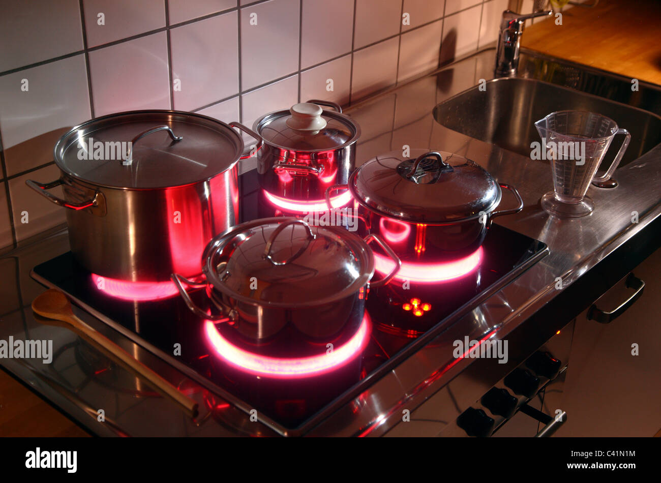 Cucina casalinga, pentole, realizzata in acciaio inossidabile, su di un vetro caldo-cottura ceramica anello. red hot incandescente. Foto Stock