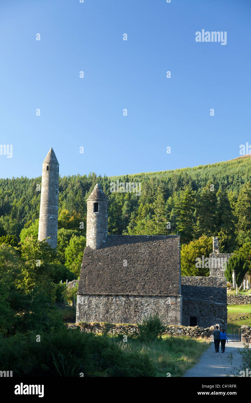 I visitatori al di sotto di San Kevin la chiesa e la torre rotonda, sito monastico di Glendalough, County Wicklow, Irlanda. Foto Stock