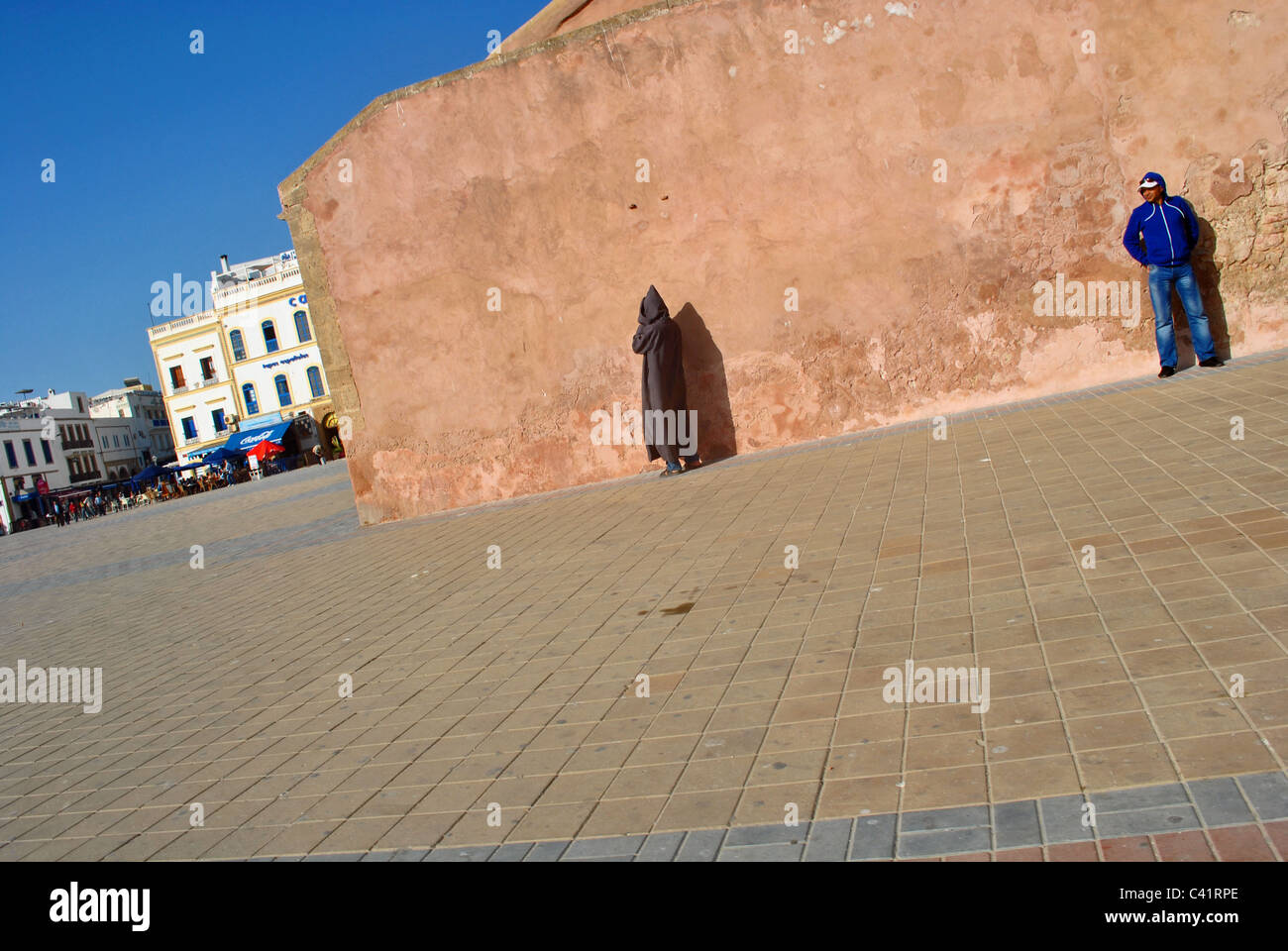 Persone stand contro un muro nella piazza principale di Essaouira, Marocco Foto Stock