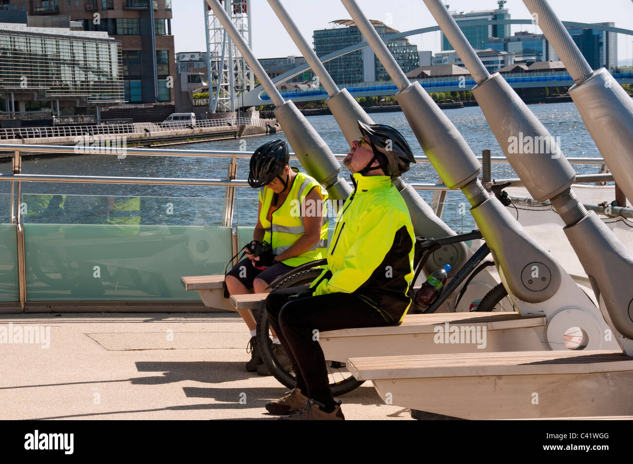 Due ciclisti in appoggio sul MediaCityUK swing passerella, Manchester Ship Canal a Salford Quays, Manchester, Inghilterra, Regno Unito Foto Stock