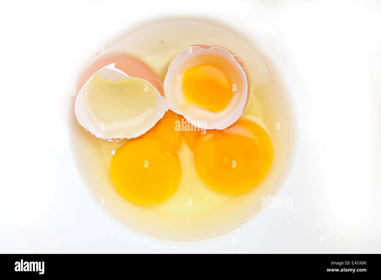 Due uova crude con il guscio delle uova in una ciotola bianco Foto Stock