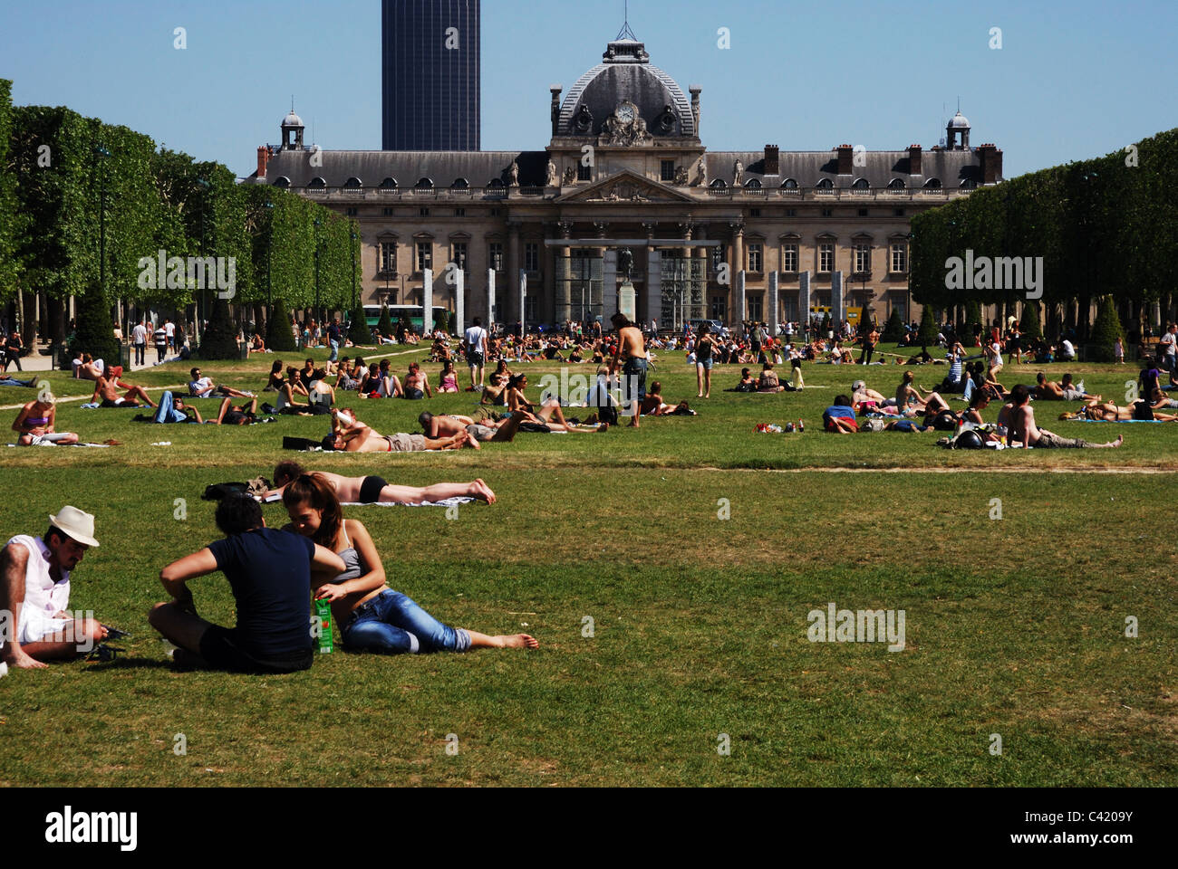 La gente a prendere il sole su Champ de Mars a Parigi con l'Ecole Militaire dietro Foto Stock