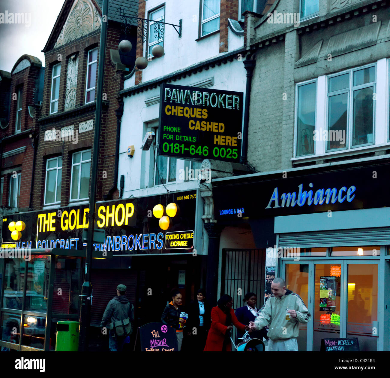 Tooting Londra Inghilterra la gente camminare passato Pawnbrokers e Bar uomo bere al di fuori Foto Stock