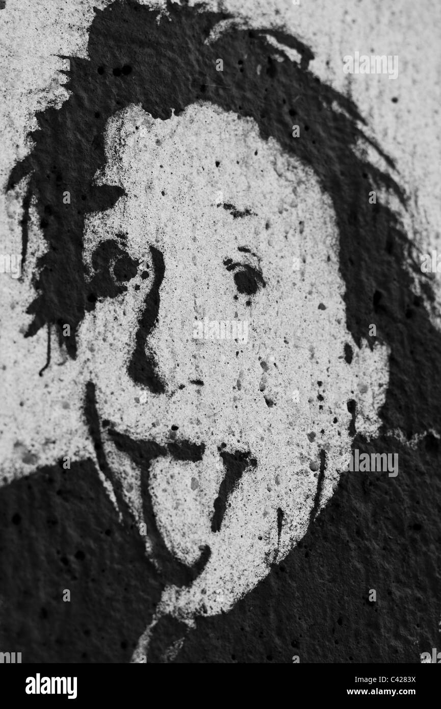 Stencil della testa di Albert Einstein inceppata / inserimenti fuori la sua lingua al visualizzatore sul grigio di un muro di cemento a Monaco di Baviera, Germania Foto Stock