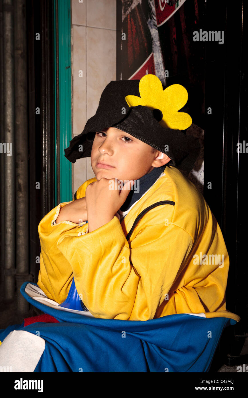 Ragazzo che guarda stanco di notte in costume seduto su una fase durante il carnevale di Santa Cruz de Tenerife Canarie Spagna Foto Stock