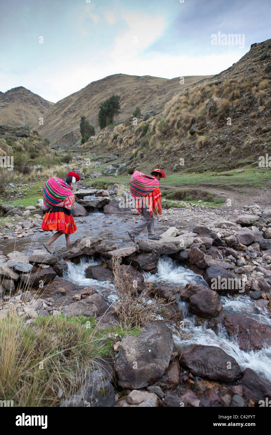 Il Perù, Patakancha, Patacancha, villaggio nei pressi di Ollantaytambo. Indian l uomo e la donna in abito tradizionale di un flusso di attraversamento. Foto Stock