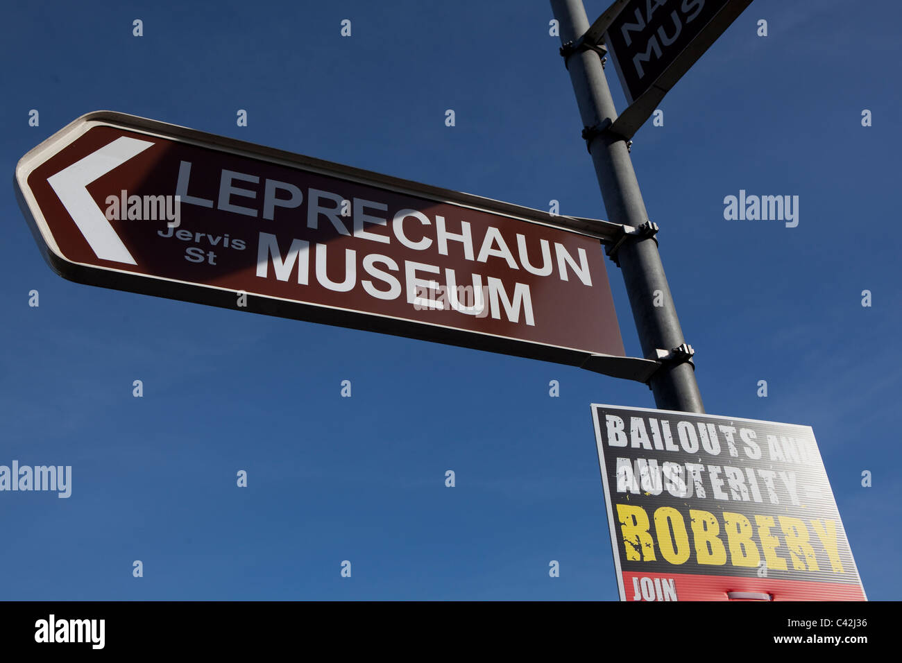 Segno per Leprechaun museum, a ponte O'Connell, Dublino, Irlanda, con manifesto politico a seguito della crisi finanziaria Foto Stock