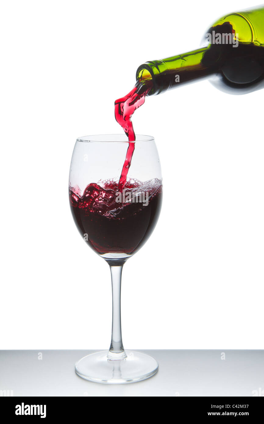 Vino rosso versando in vetro del vino isolato Foto Stock