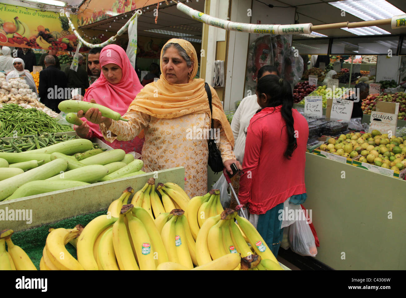 Donne asiatiche rovistare per frutta e verdura in un negozio a Wembley. Il centro della città ha una alta concentrazione di sud asiatici. Foto Stock