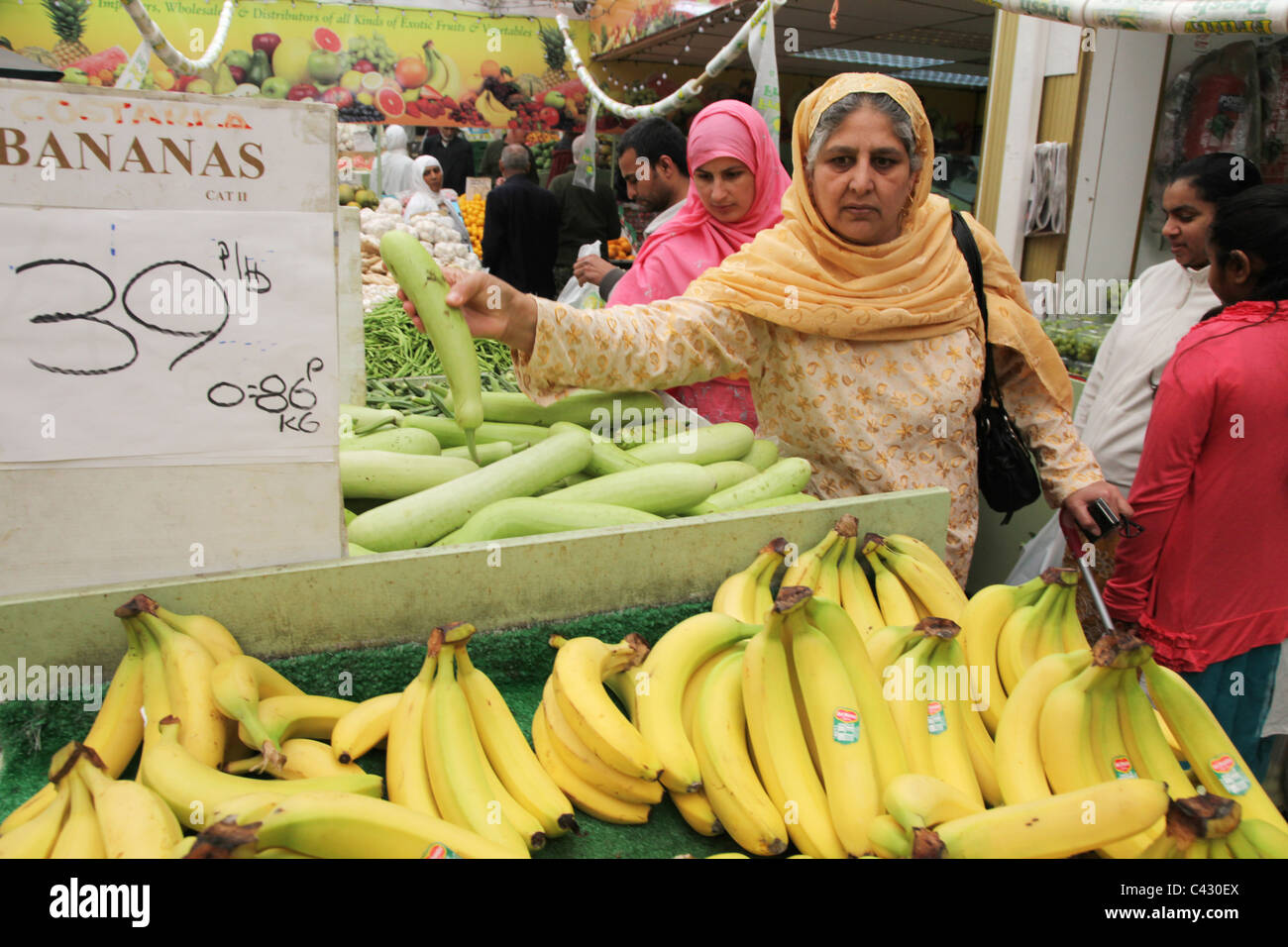Donne asiatiche rovistare per frutta e verdura in un negozio a Wembley. Il centro della città ha una alta concentrazione di sud asiatici. Foto Stock